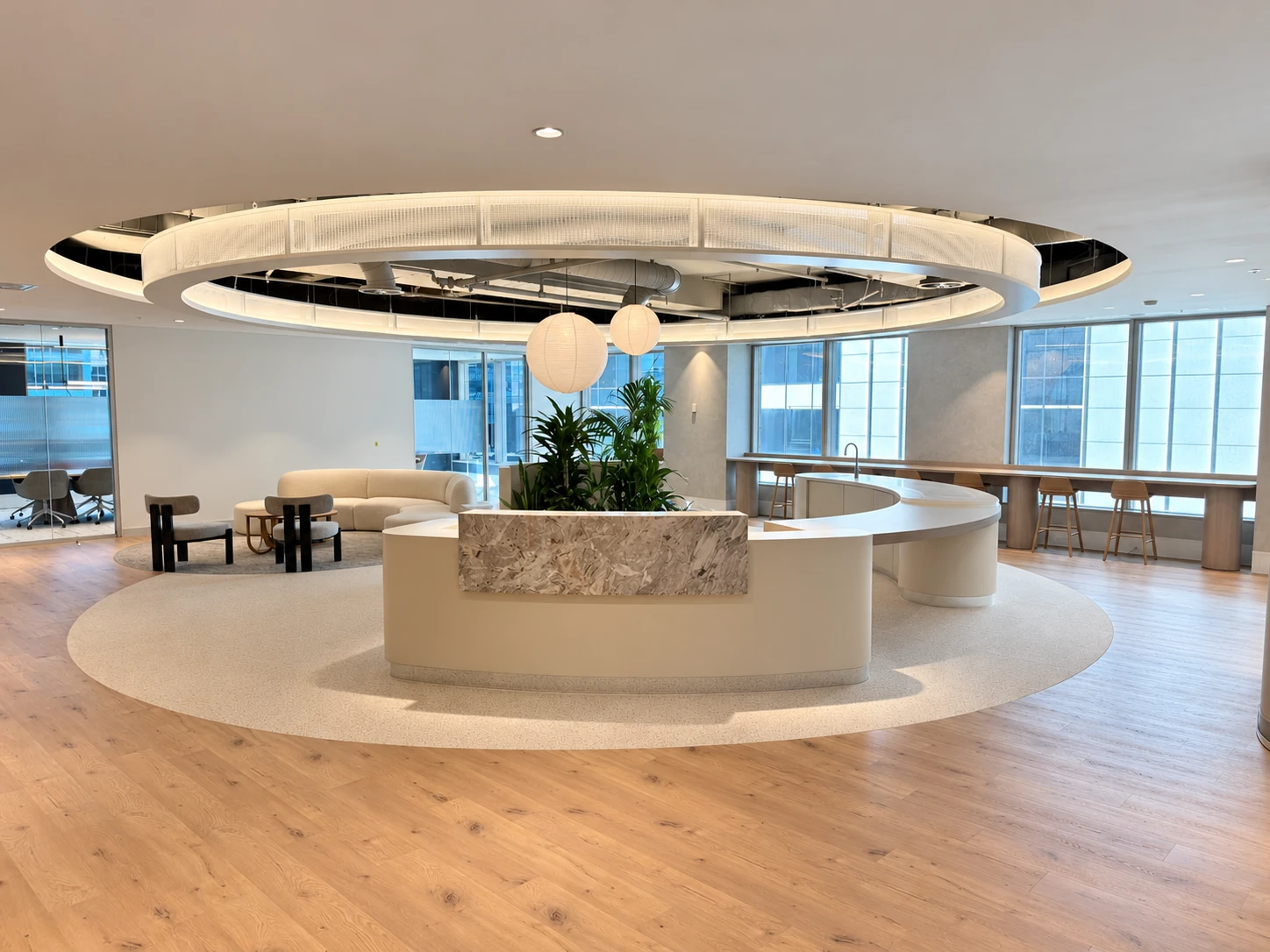 Curved reception desk with a natural stone front feature below a circular ceiling feature